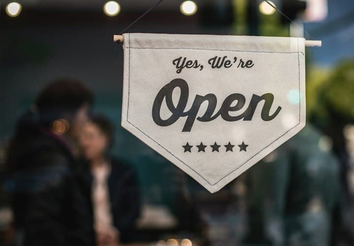 "Yes, we're open" sign in a local business window